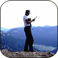 Scott standing on a mountain and holding research equipment