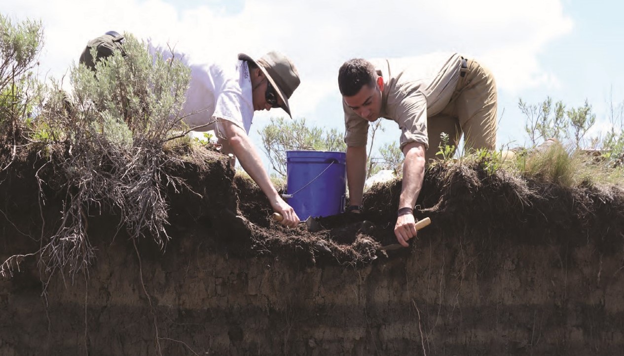 Two people digging with trowels.
