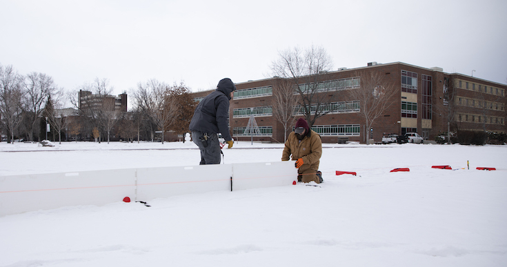 two men install ice rink boards